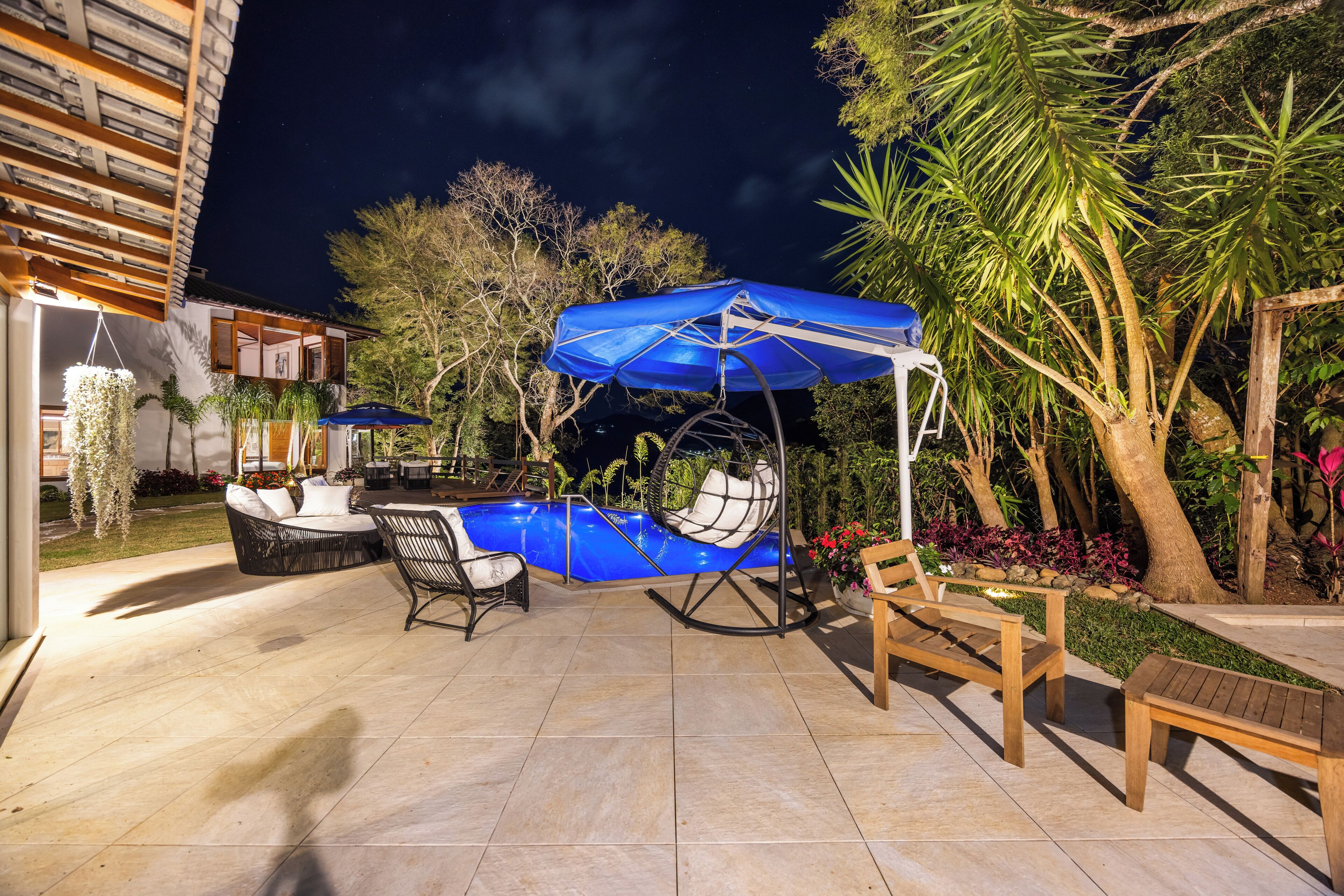 Un patio exterior con piscina, sillones de descanso y una silla colgante.