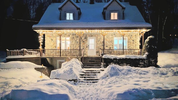A stone house with a porch, steps leading to the front door, and snow on the ground. - Cozy Nature Cottage Retreat – Relax, Unwind & Recharge (Notre-Dame-de-Pontmain)