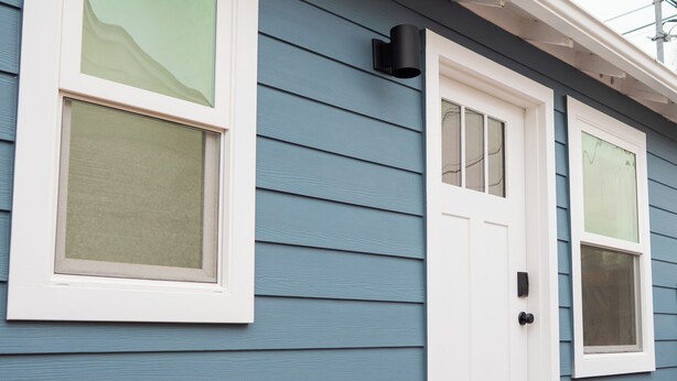 A blue house with a white door, a window, and a small porch with steps. - Brand-New Furnished Studio ADU for Mid-Term Stays (San Mateo)