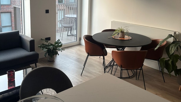 Ein modernes Wohnzimmer mit einer Couch, einem Esstisch, Stühlen und einer Obstschale.