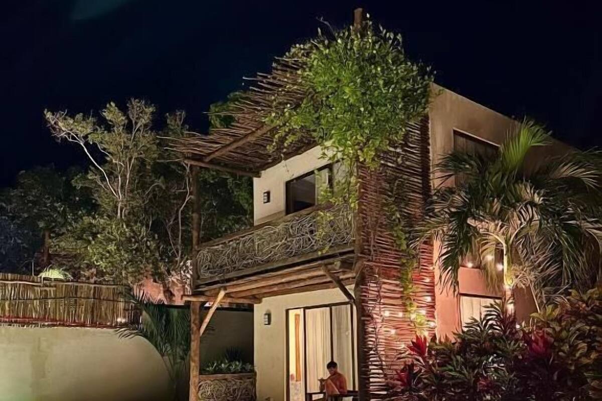A two-story house with a swimming pool at night.