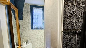 A bathroom with a toilet, a window, and a shower with mosaic tiles. - The Queen's Hideaway (Fontainebleau)