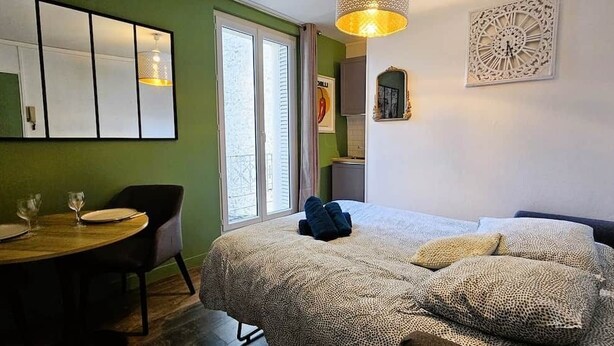 A room with a bed, a small table with two glasses and plates, a chair, and a window with curtains. - The Queen's Hideaway (Fontainebleau)