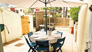 Un patio con una mesa redonda para cuatro personas, rodeada de sillas, bajo un paraguas grande.