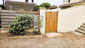 Una propiedad residencial con un portón de madera, un pequeño jardín y una escalera que conduce a una zona cubierta.