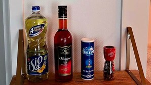 Une pancarte dans la cuisine avec une bouteille d’huile de Graines Omega 3, une bouteille de vin Maille, une canette de bière Balengue et une bouteille de poivre Moulard.