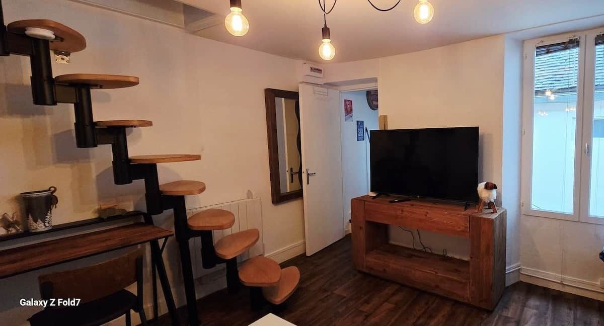 Een moderne woonkamer met een houten trap, een flatscreen televisie en een eethoek met een Galaxy Z Fold7.