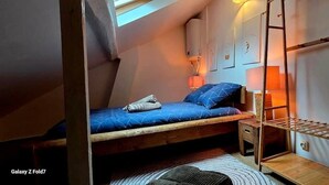 Une chambre à coucher de style loft, compacte, avec un lit superposé, un petit bureau et une échelle.