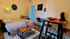 Een gezellige slaapkamer met een bed, nachtkastje, lamp en een klein bureau met een stoel.
