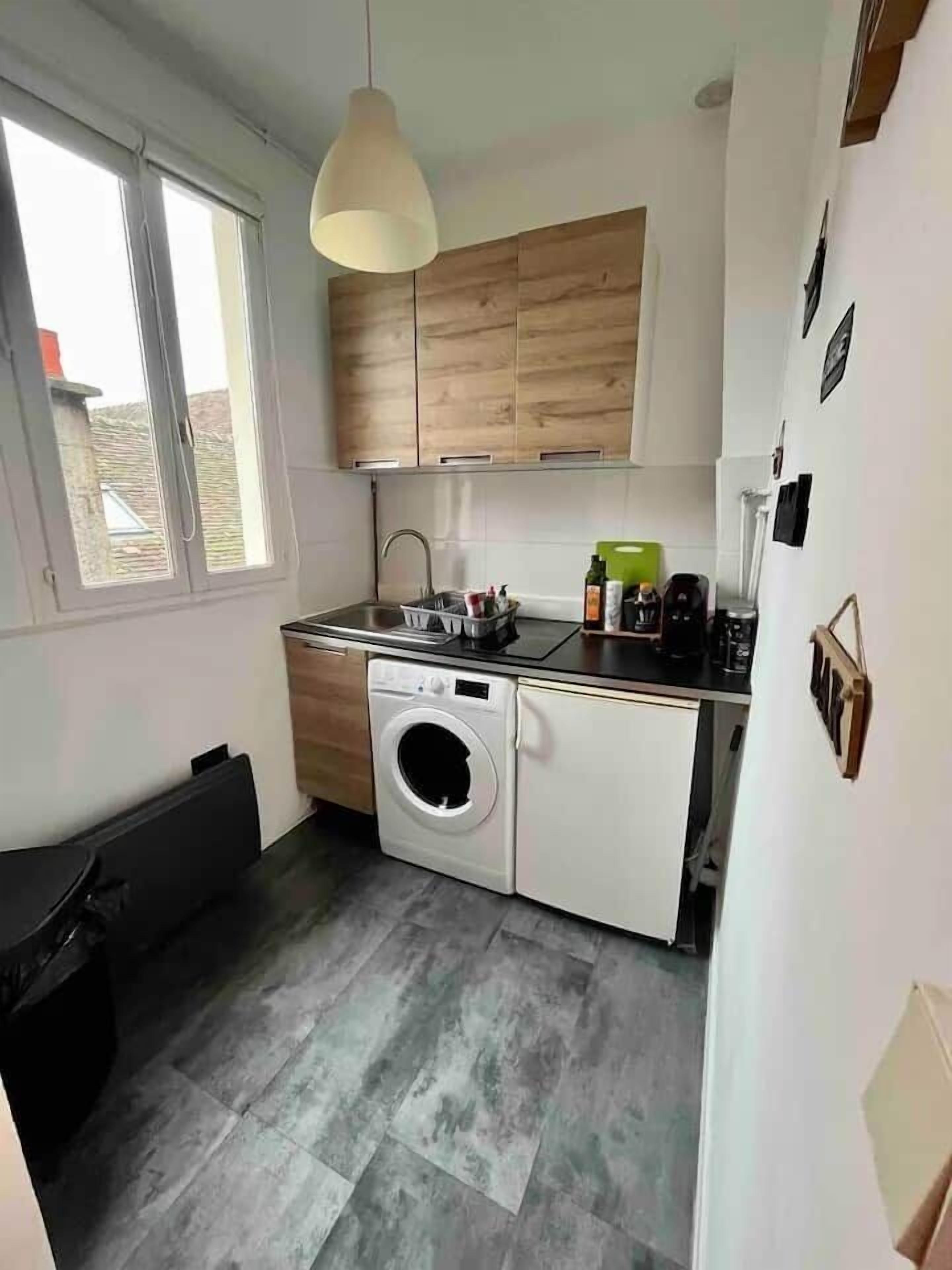 A compact kitchen with a washing machine, a sink, and a window.