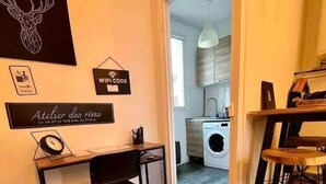 Een moderne keuken met een wasmachine, een eethoek met een tafel en stoelen, en een bureau met een stoel.