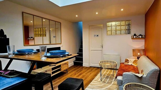 A compact living space with a dining area, a sofa, a small table, and a chair. - La Cachette Oubliee (Melun)