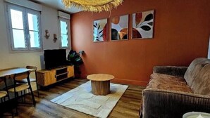 Una sala de estar con sofá, una mesa de centro, un mueble para televisor y un comedor con sillas.
