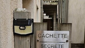 Una verja de madera con un candado de metal y un cartel que dice 'CACHETTE SECRETE'.