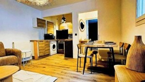 Un espacio habitable compacto con cocina, comedor y una pequeña zona de estar.