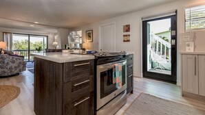 Una cocina moderna con una isla central, horno empotrado y un amplio ventanal.