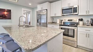 Una cocina moderna con armarios blancos, electrodomésticos de acero inoxidable y encimera de granito.