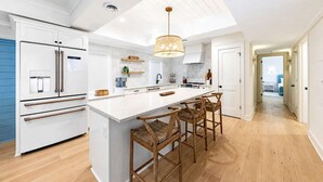 A modern kitchen with a central island, bar stools, and a ceiling light fixture. - Bright 2bd w. Chef's Kitchen, 1 Block to King! (Charleston)