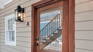 A wooden door with a glass panel, a keypad lock, and a black lantern light fixture above it. - Bright 2bd w. Chef's Kitchen, 1 Block to King! (Charleston)