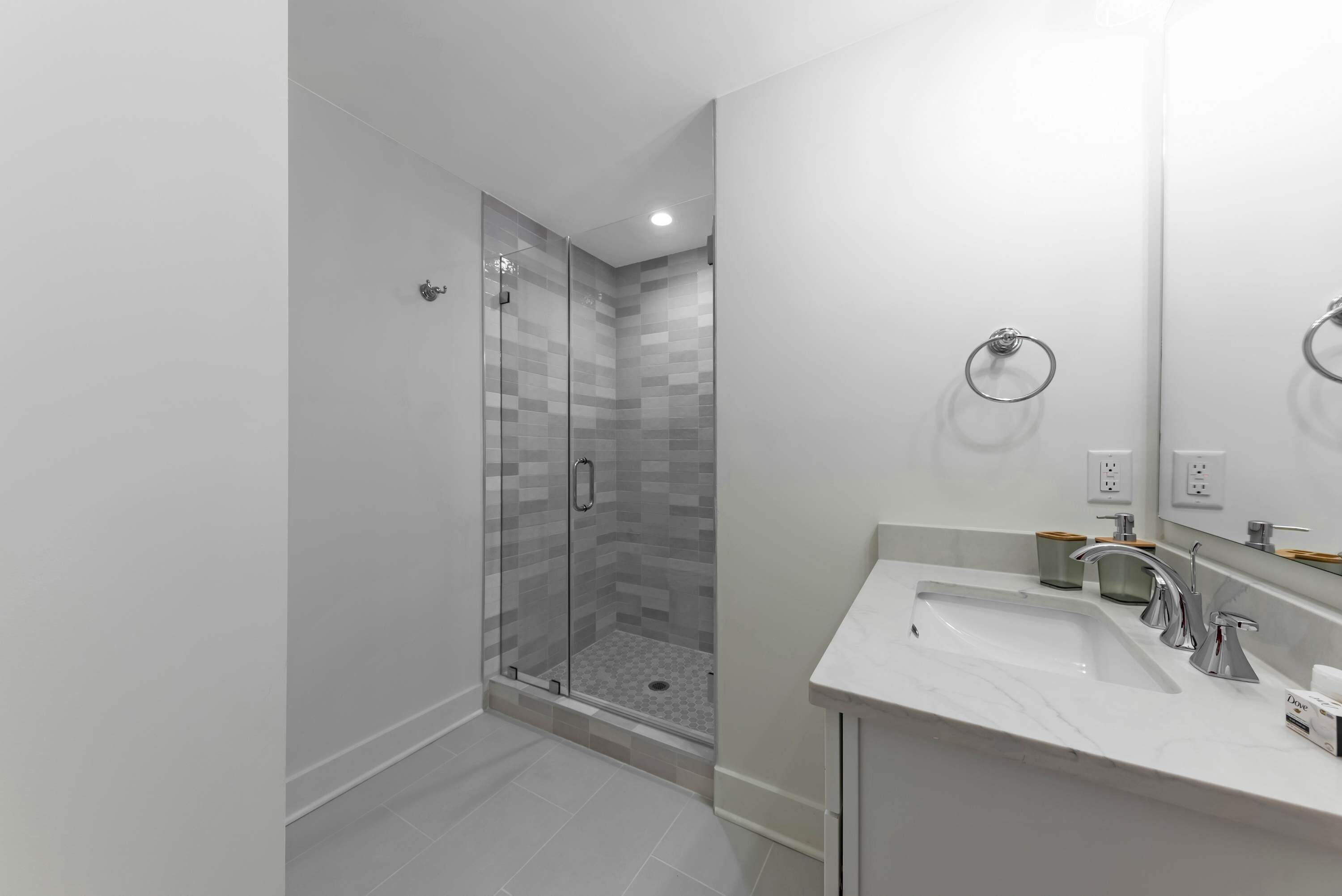 A modern bathroom with a glass shower enclosure, a sink with a mirror, and a toilet.