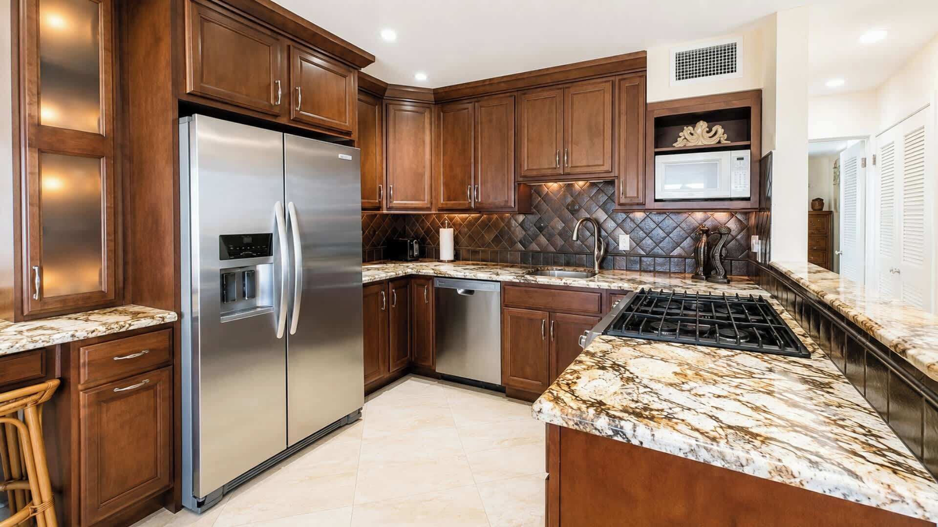 A kitchen with dark wooden cabinets, stainless steel appliances, and a marble countertop.