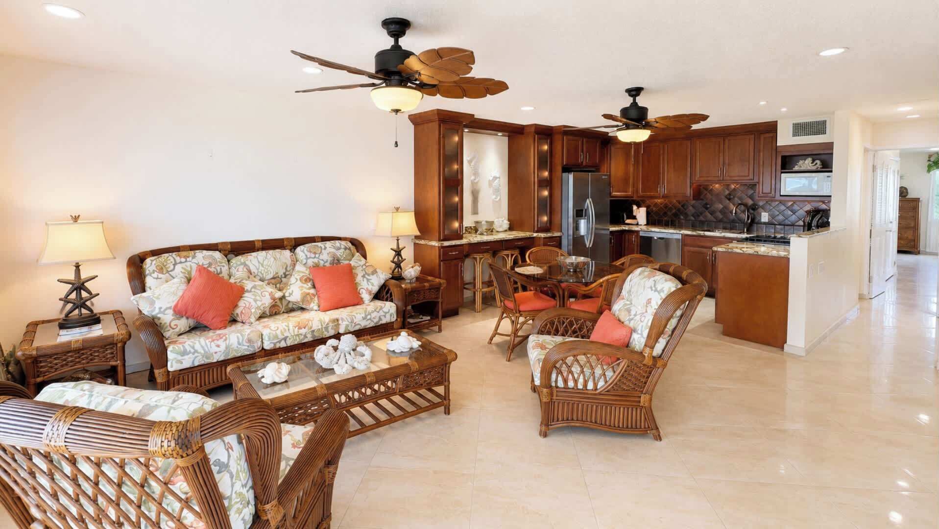 A spacious living room with a sofa, chairs, a coffee table, and a kitchen area with a refrigerator and stove.