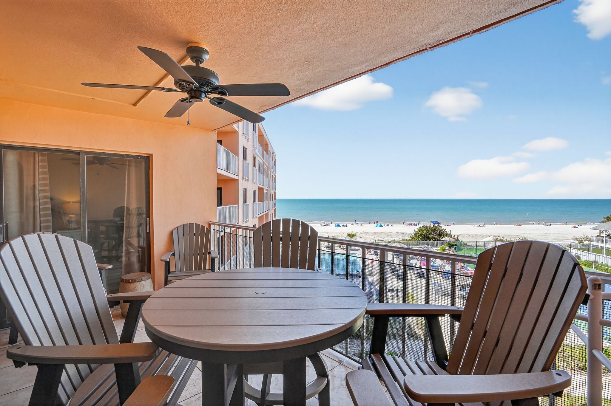 Covered balcony with outdoor dining seating and beachfront views.