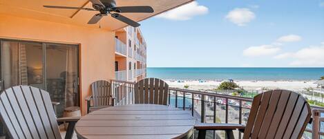 Covered balcony with outdoor dining seating and beachfront views.