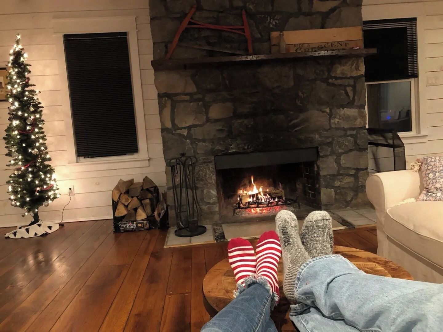 Una sala de estar acogedora con chimenea de piedra, un árbol de Navidad y un televisor.