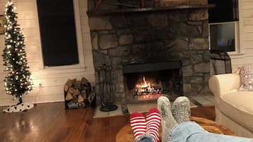 Una sala de estar acogedora con chimenea de piedra, un árbol de Navidad y un televisor.