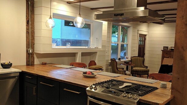 Una cocina moderna con armarios oscuros, una estufa de acero inoxidable y una encimera de madera.
