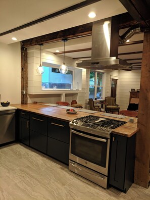 A modern kitchen with dark cabinets, a stainless steel stove, and a wooden countertop. - Carriage House Apartment Goshen NY (Goshen)