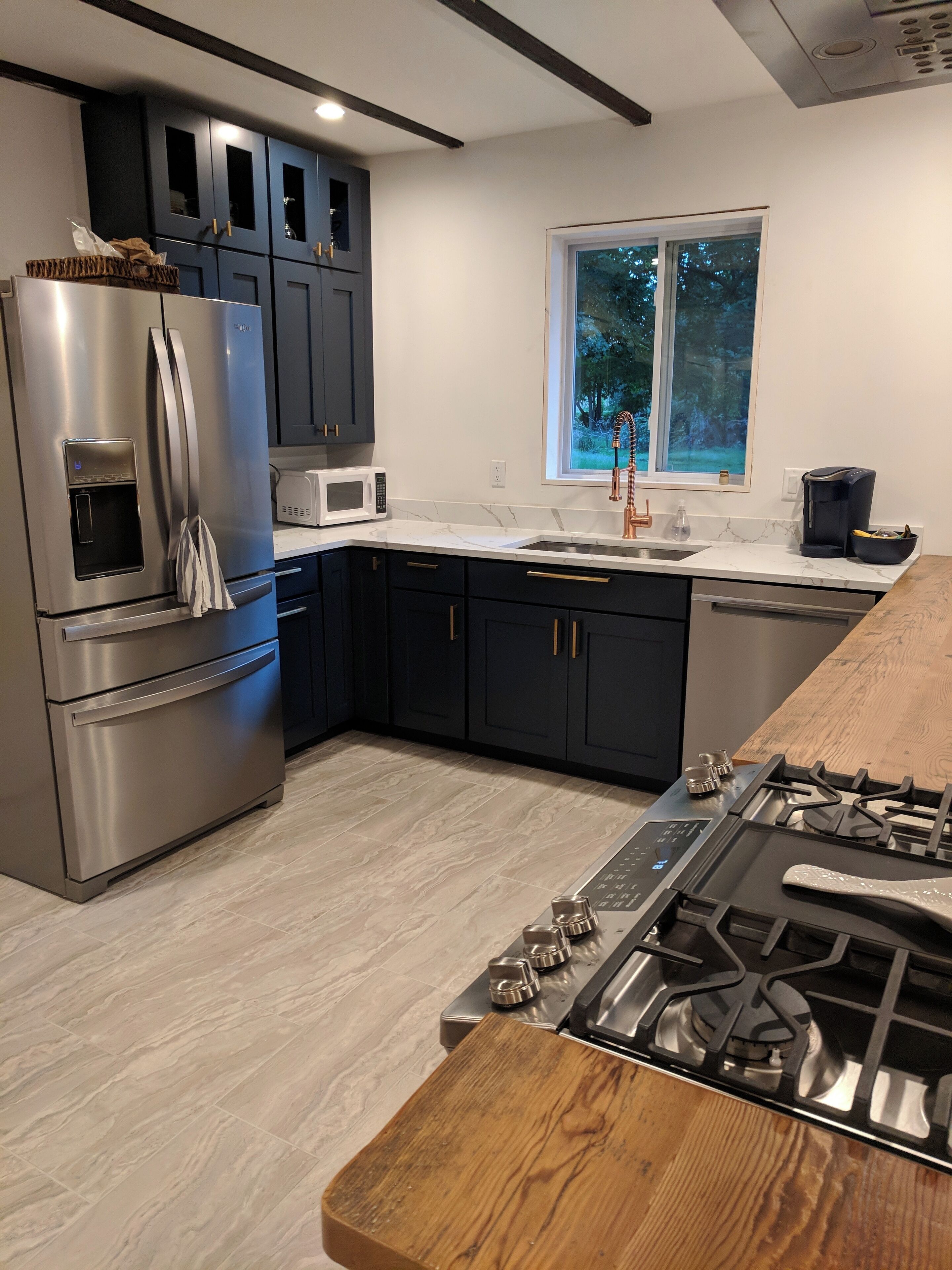 A modern kitchen with a stainless steel refrigerator, a microwave, a sink, and a gas stove.