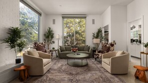 A modern living room with a large window, two sofas, a coffee table, and decorative plants.