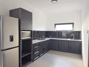 Una cucina moderna con mobili scuri, un dispenser integrato per l'acqua e una finestra sopra il lavello.