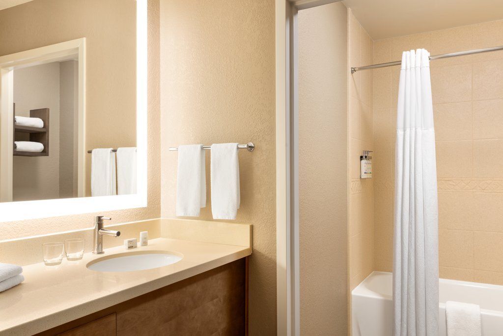 A bathroom with a sink, mirror, towel rack, and shower curtain.