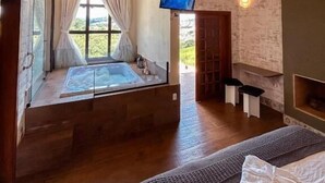 Quarto com uma cama grande, banheira de hidromassagem, televisão e lareira.
