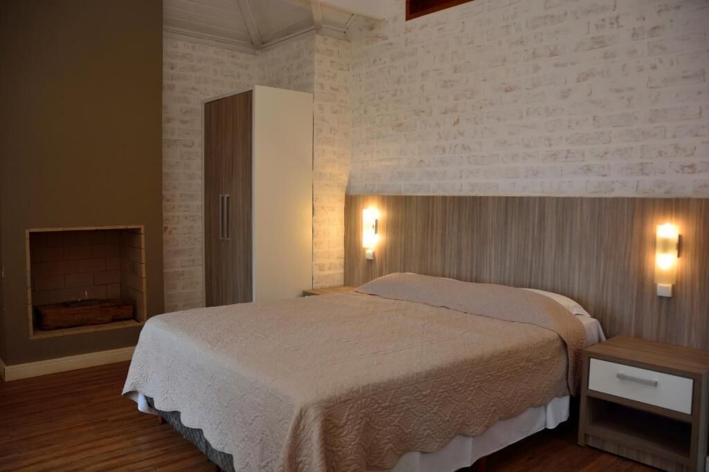 A bedroom with a bed, nightstands, a wardrobe, and a brick-patterned wall.