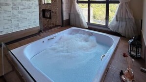 Quarto com uma banheira grande, uma janela com cortinas, um espelho na parede e teto de madeira.
