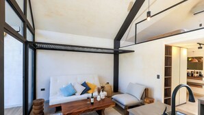 Een moderne woonkamer met een bank, salontafel en een keukenhoek met een spoelbak en aanrecht.