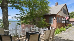 Een blokhut met een witte picket fence, een tafel en twee stoelen ervoor.