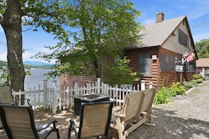A log cabin with a white picket fence, a table, and two chairs in front. - Lakefront Cottage #3 | Dock | Mtn & Lake Views (Bristol)