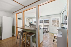 A kitchen with wooden stools, a white refrigerator, and a window with a view of the outside. - Lakefront Cottage #3 | Dock | Mtn & Lake Views (Bristol)