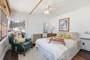 A bedroom with a bed, a chair, a desk, a ceiling fan, a window, and a painting. - Lakefront Cottage #3 | Dock | Mtn & Lake Views (Bristol)