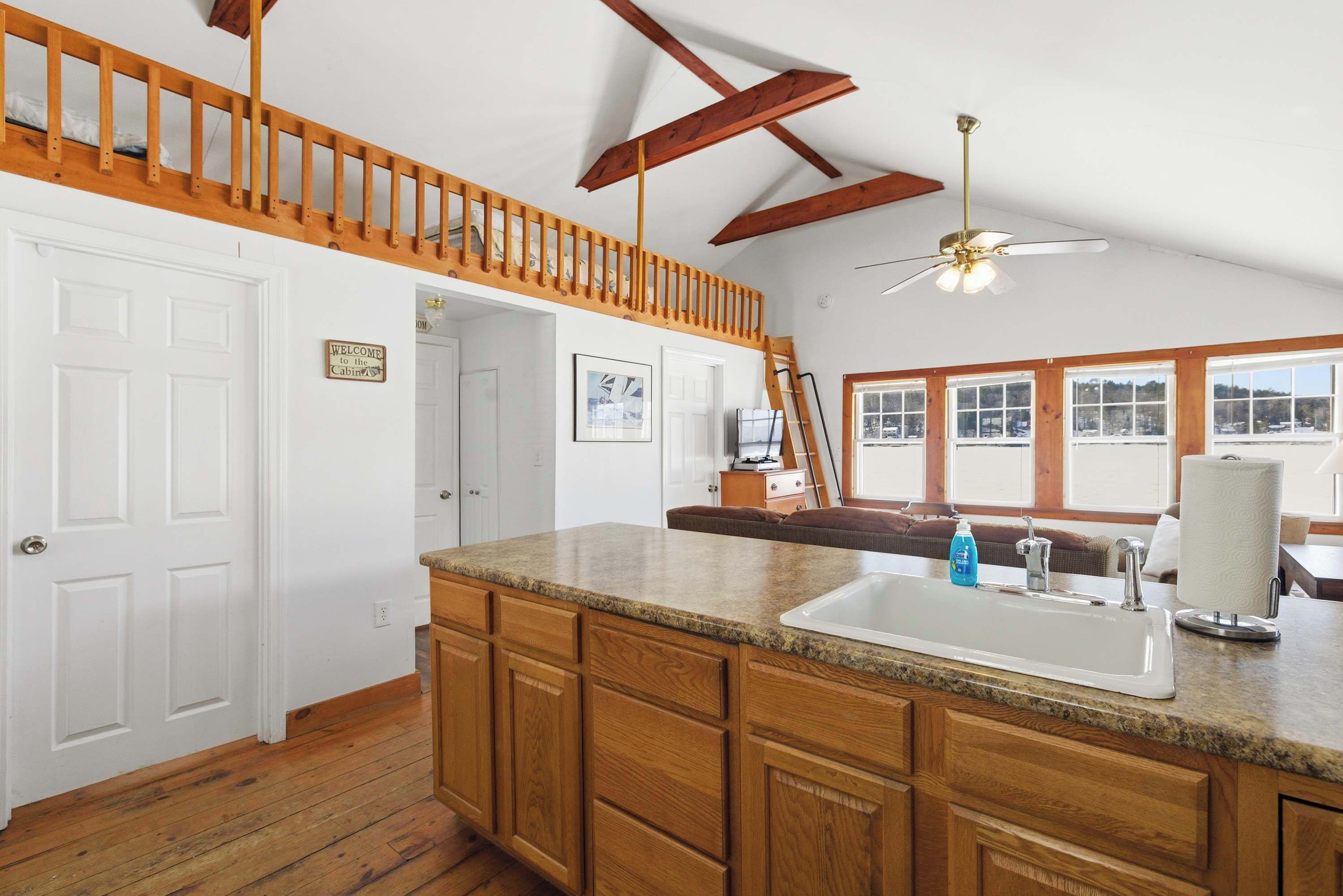 A kitchen with wooden cabinets, a granite countertop, a sink, and a ceiling fan.