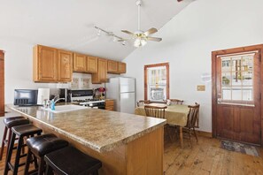 A kitchen with wooden cabinets, a granite countertop, a built-in stove, and a ceiling fan. - Lakefront Cottage #2 | Dock | Mtn & Lake Views (Bristol)