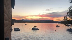 A calm lake with boats at sunset, a wooden dock, and distant mountains.