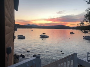 Un lac paisible où flottent des bateaux au coucher du soleil, une jetée en bois et des montagnes lointaines.