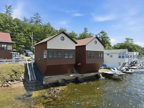 Two wooden cabins with a small dock extending into a body of water, surrounded by trees and other buildings. - Lakefront Cottage #6 | Dock | Mtn & Lake Views (Bristol)