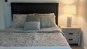 A neatly made bed with patterned bedding, a bedside lamp, and a nightstand with a drawer. - Fabulous 4-bedroom 2.5 bath Lake Cottage (Montgomery)